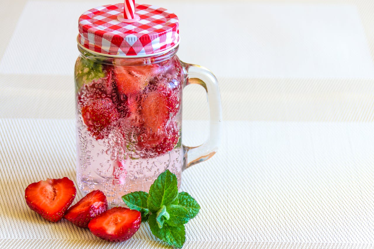 about-us-02 Mason jar of strawberry-infused sparkling water with mint, perfect for summer refreshment.